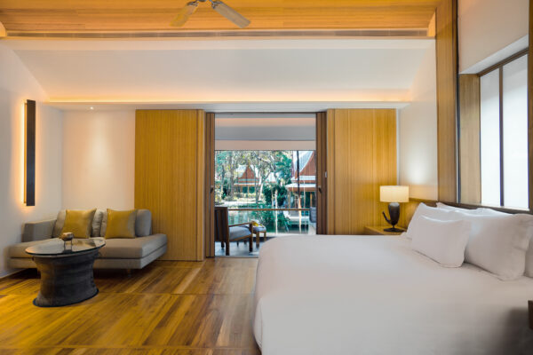 Stylish resort accommodation featuring a cosy bedroom with a spacious bed, and views of lush greenery.